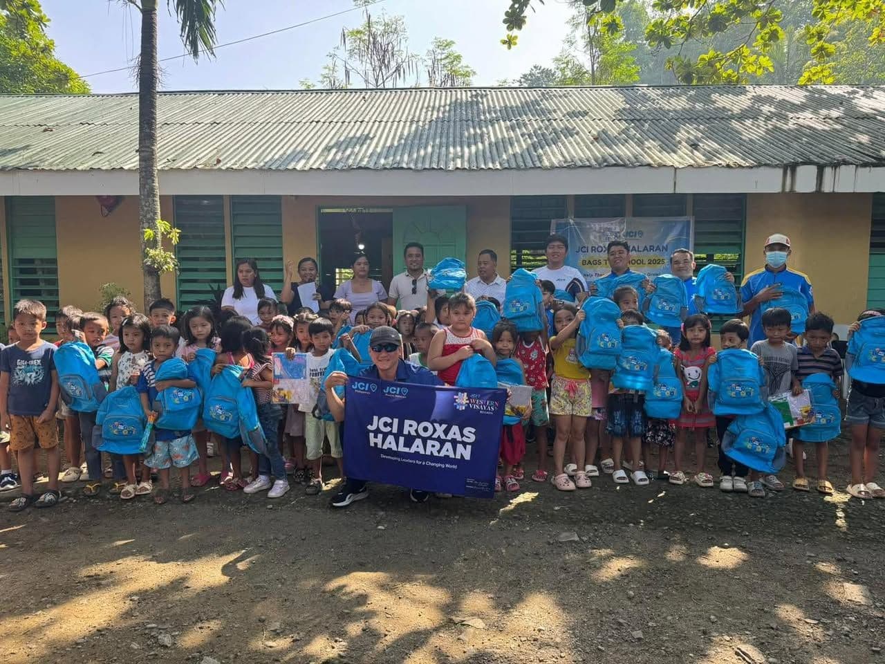 Pupils with new blue school bags and JCI Roxas Halaran members at a school grounds