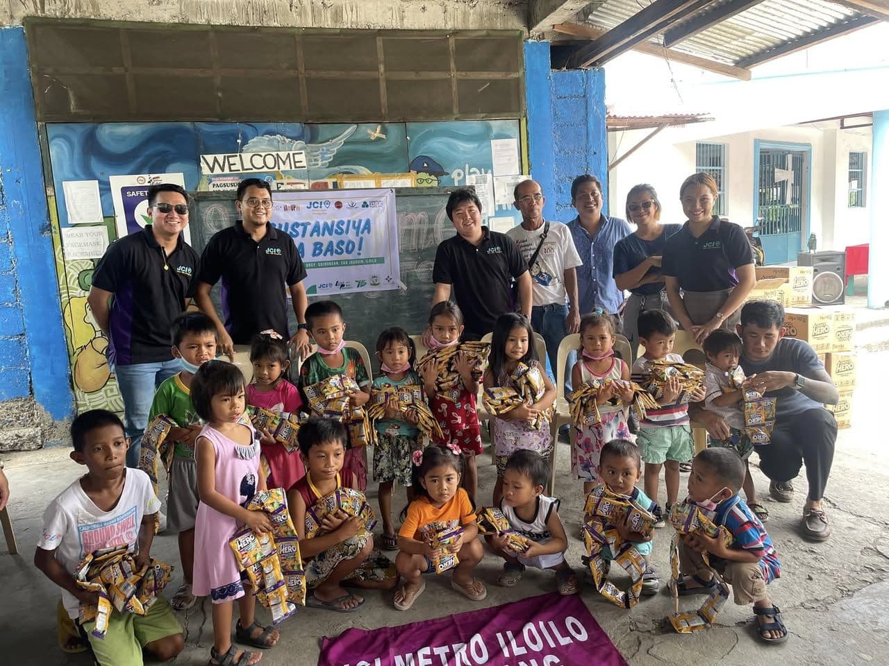 Children receiving milk drinks from JCI Roxas Halaran members at a day care center